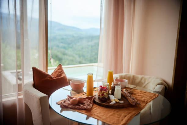 Healthy breakfast of orange juice, fresh fruit, nuts and muesli sitting on a dining table with eggs and baguettes in the morning