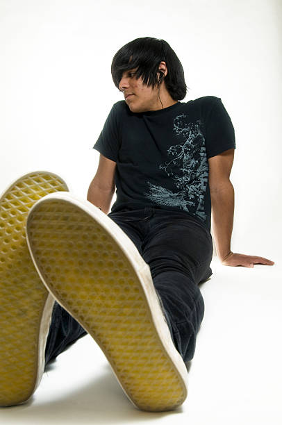 Teen dressed in black sitting on white background forced perspective Teen dressed in black sitting on white background forced perspective depth of field emo hair guys stock pictures, royalty-free photos & images