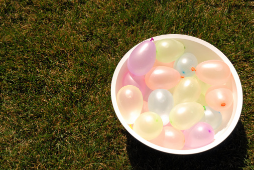 This is a picture of a bowl of water balloons on the green grass.