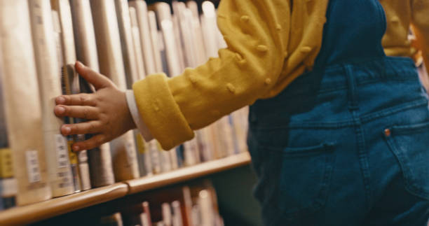 istock Bookshelf, library and hands of child on books for reading, learning and educational development. Retail bookstore, childhood and young girl searching for fairytale story, novel and kids literature 1460016895