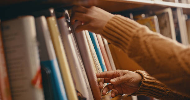 istock Library, knowledge and hands with books on bookshelf for reading, learning and educational research. Bookstore, information and girl search, select and choose textbook, academic journal or literature 1460018118