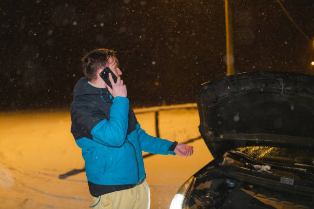 istock Stressed young man talking on the phone while standing in front of his stuck car 1460019659