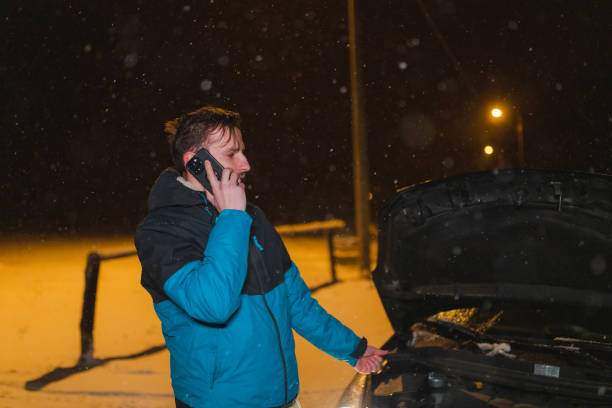 istock Stressed young man talking on the phone while standing in front of his stuck car 1460020210
