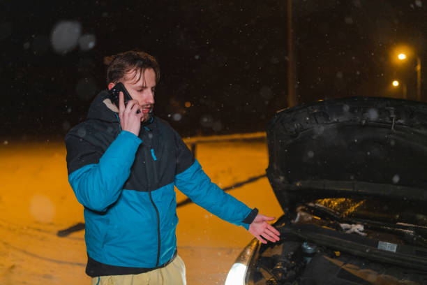 istock Stressed young man talking on the phone while standing in front of his stuck car 1460020227