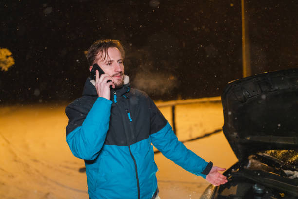 istock Stressed young man talking on the phone while standing in front of his stuck car 1460020255