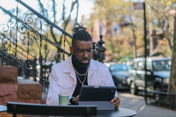 istock man sitting in a NY cafe, finishing work on a digital tablet 1460023779