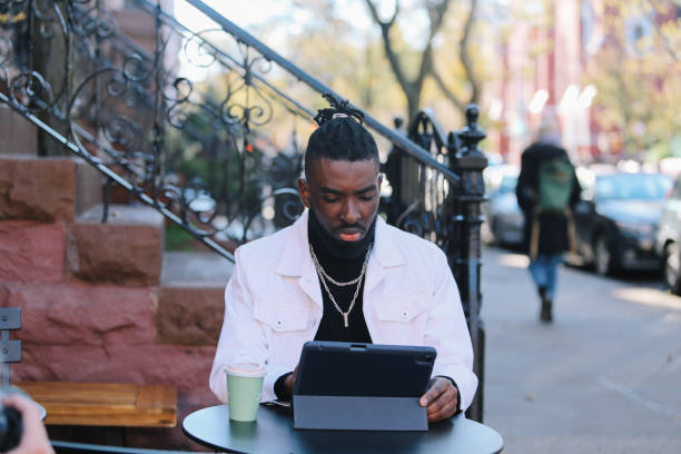 istock man sitting in a NY cafe, finishing work on a digital tablet 1460024383