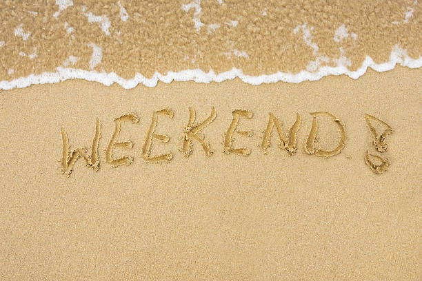 Sandy beach with word Weekend written on sand stock photo