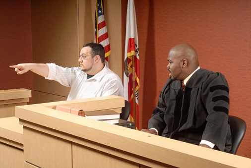 Man acting as a witness pointing out someone to the judge