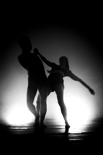 modern ballet dancers performing. motion blur and smoke in the air