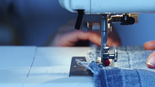 Close-up view of a woman's hands working on a sewing machine.