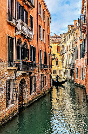 Photo of one of the many waterways in Venice, Italy, with a rear view of a Gondolier in the distance