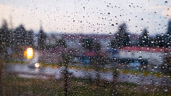 Slowly dripping raindrops and blurred lights from the windowpane