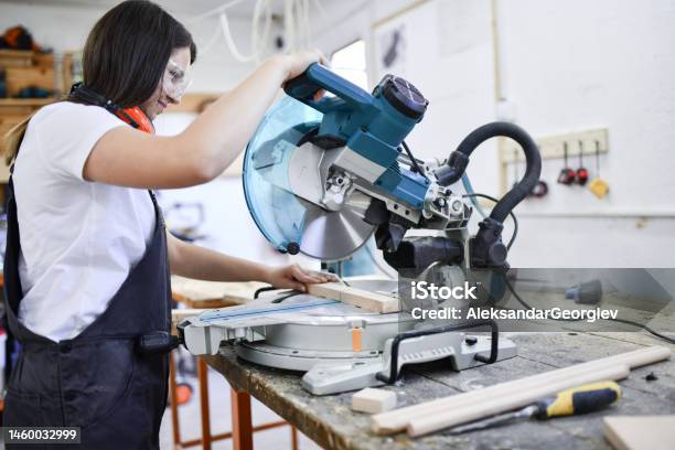 Female Carpenter Expertly Cutting Piece Of Wood Stock Photo - Download Image Now - Carpenter, Cutting, Wood - Material