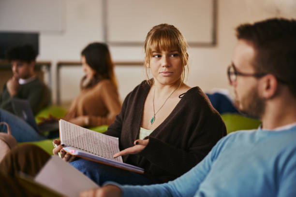 istock Female student talking to her friend while studying at campus. 1460033133
