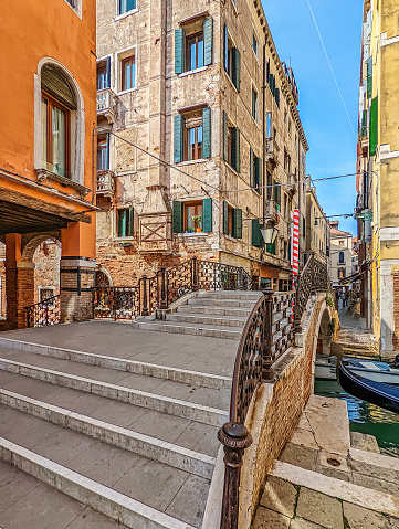 Photo of a steps leading to a bridge crossing over a canal in Venice, Italy, with surrounding architecture