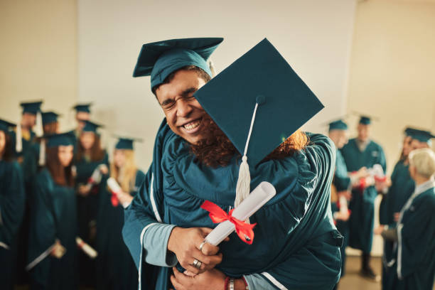 Happy university couple congratulating each other on graduation. Happy college couple embracing while celebrating their graduation in a lecture hall. african university students stock pictures, royalty-free photos & images