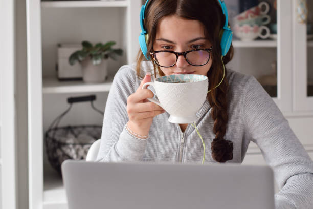 istock Young girl in headphones drinking coffee while studying 1460033463