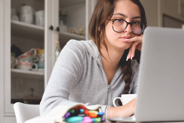 istock Young girl in glasses sitting at desk using laptop computer 1460033465