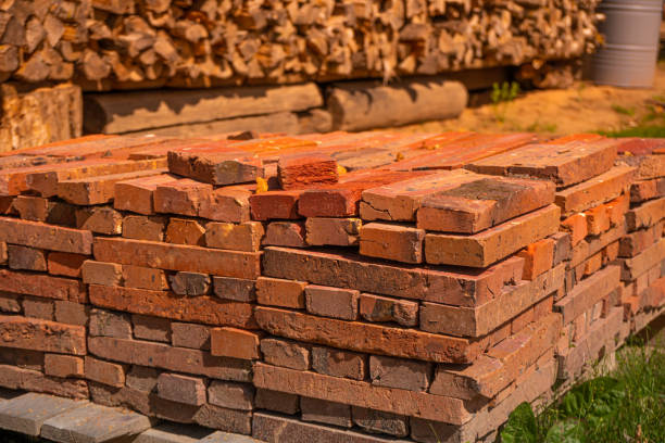 istock Red brick packed in stack are stored on ground outdoors at a hardware store warehouse. Building bricks on pallet on an outdoor warehouse 1460033693
