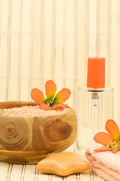 Bodycare products, fragrance bottle, soap, bath salt, towel and decoration flowers on bamboo, focus on bottle