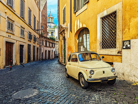 Photo of a small yellow car parked by the side of a street in Rome