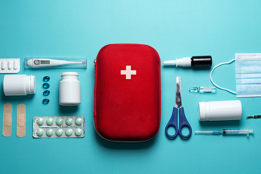 Home first aid kit on a blue background. The elements of the first aid kit