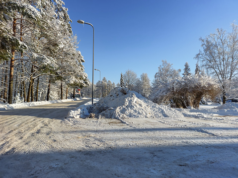 Winter landscape. View of an urban scenery with hugepile of snow on the side of the road and surroundings of trees with all its branches covered with snow after a heavy snowfall on a sunny day