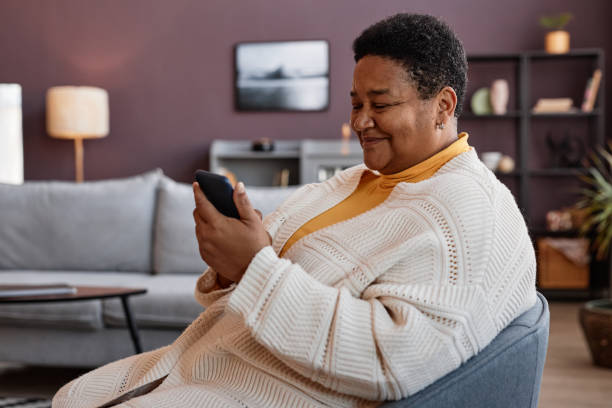 istock Senior black woman using smartphone while relaxing in cozy home 1460038871