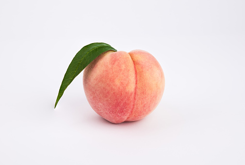 One fresh peach on a white background. Close-up from the front.