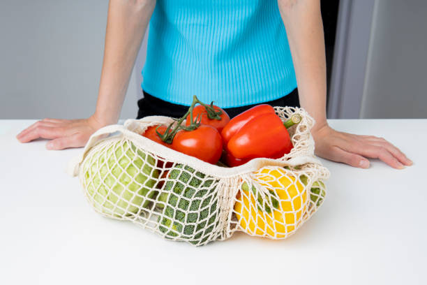 istock Standing woman near table with bag with fresh vegetables on white table 1460040534