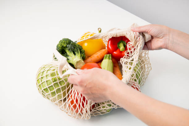 istock Women's hands take out fresh vegetables from a bag on a white table. Top view, flat lay 1460040604