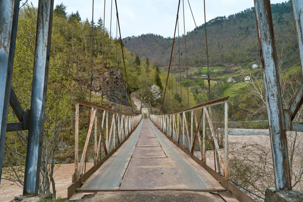 istock Wobbly old bridge over a mountain river for cars. 1460042983