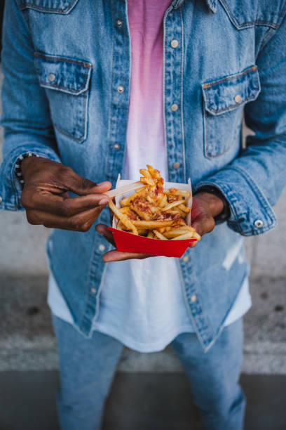 istock Anonymous man standing eating french fries 1460046554