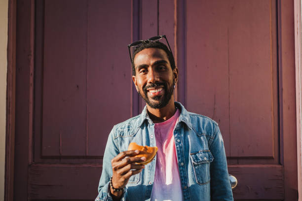 istock Man holding cheeseburger on the street 1460046579