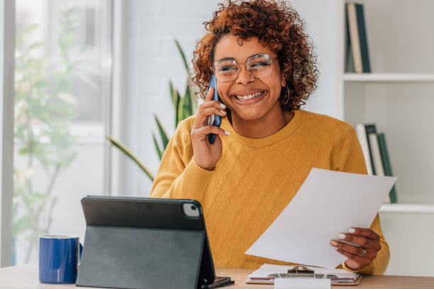 istock woman at home with laptop talking on mobile phone with document 1460049132
