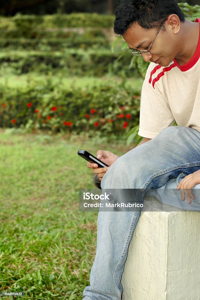 Asiatique homme souriant et à envoyer des SMS - Photo de Adulte libre de droits