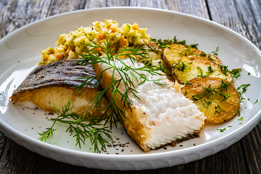 Fried cod loin fillet with mashed potato and vegetable salad served with fresh lemon.