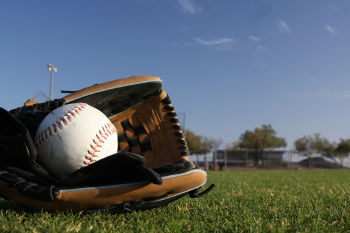 Selective focus of man holding baseball ball isolated on black background.