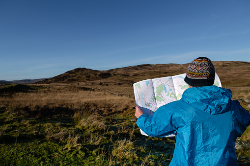 Senior man looking at a map in a remote rural location in Scotland on a bright winter morning