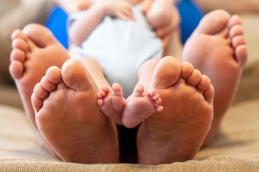 Close up frontal photo of the feet of the father, mother and the baby newborn boy.