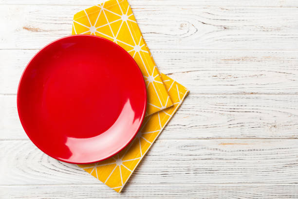 istock Top view on colored background empty round red plate on tablecloth for food. Empty dish on napkin with space for your design 1460064018