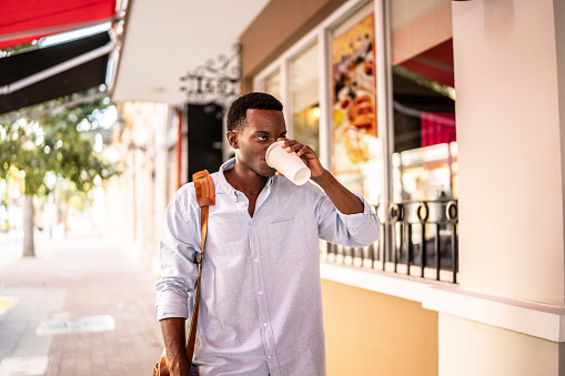 Young business man walking and drinking coffee