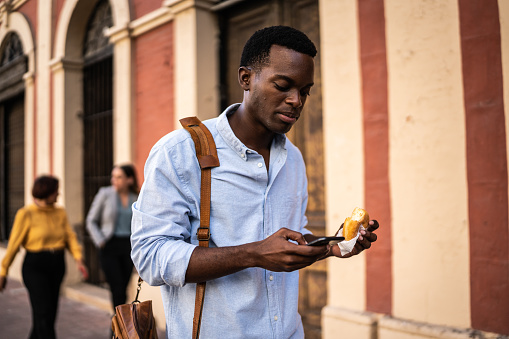 Young man using cellphone while walking outdoors