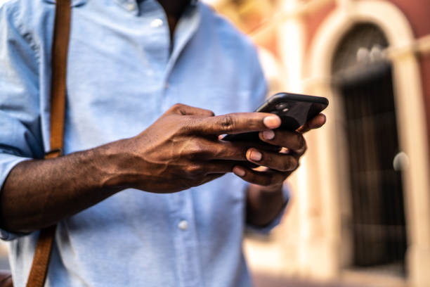 istock Close-up of man using mobile phone while walking outdoors 1460066606
