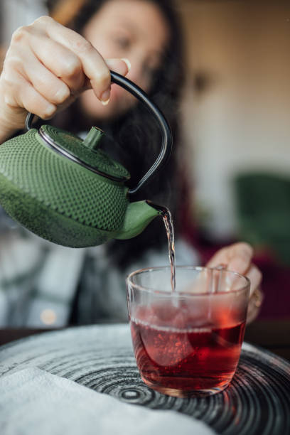 istock Pouring hot aromatic herbal tea from teapot into cup 1460067782