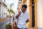 Young man celebrating using mobile phone while walking outdoors