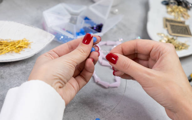 Close hand jeweler stringing pearls on a necklace
