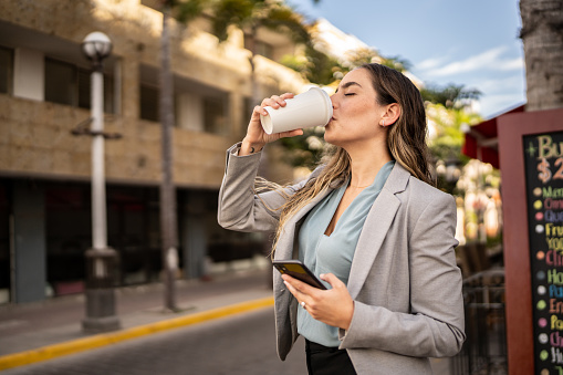 Mid adult businesswoman drinking coffee cup outdoors