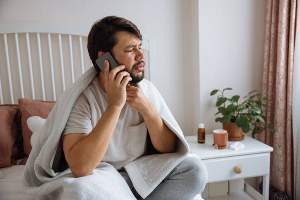 istock Sick man with the flu speaking to a virtual doctor 1460073204
